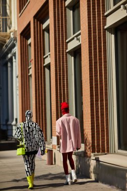 NEW YORK, USA - NOVEMBER 26, 2022: Back view of glamour couple walking along autumn avenue in new york city, metropolis residents clipart