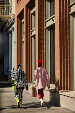 NEW YORK, USA - NOVEMBER 26, 2022: Back view of extravagant couple walking along autumn street in new york city, stylish pedestrians clipart