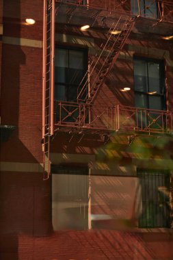Sonbaharda New York şehrinde yangın merdivenleri ve gölgeleri olan klasik kırmızı tuğla bina.