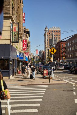 NEW YORK, USA - NOVEMBER 26, 2022: pedestrians walking along busy street in asiatown clipart