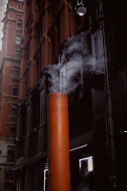 New York 'un bulanık arka planında, taş binaların yakınındaki caddede buharlı havalandırma borusu.