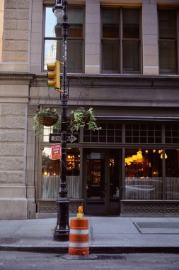 New York 'ta trafik ışıkları ve saksıları olan sokak direğine yakın restoranı olan bir bina.