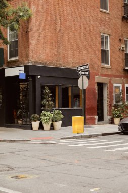 New York 'ta kentsel caddenin kesiştiği yerde dükkan önü ve saksıları olan tuğla bina.