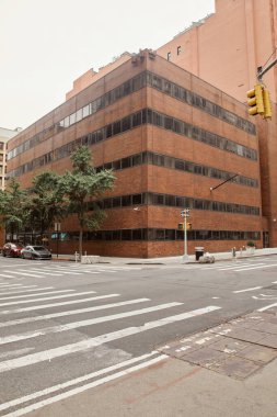 New York 'un kentsel caddesinde yaya geçidi olan kavşaktaki modern tuğla bina.