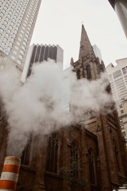 Kırmızı tuğlalı Katolik kilisesi ve New York 'ta buhar yakınında gökdelenler alçak açılı.