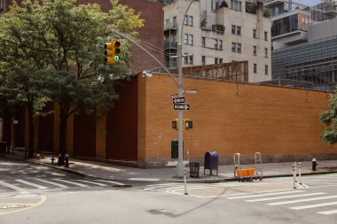 brick fence near road pole with traffic light of crossroad with pedestrian crossing in new york city clipart