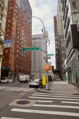 Yaya geçidi üzerindeki trafik işaretleri ve New York 'ta geniş bir yolda hareket eden arabalar, metropol sahnesi.