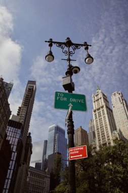 New York 'taki gökdelenlere karşı fener ve trafik işaretleriyle sokak direğinin alçak açılı görüntüsü