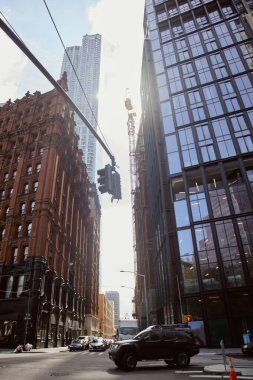 New York 'ta modern ve klasik binaların yakınında trafik ışığı olan kavşakta giden arabalar.