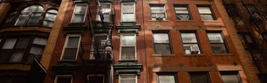 low angle view of vintage red brick house with fire escape stairs in new york city, banner clipart