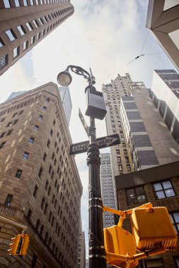 New York 'taki yüksek binanın yakınındaki trafik ışıklarıyla sokak direğinin alçak açılı görüntüsü.