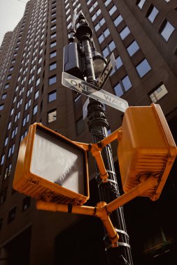New York şehrinin modern binasının yakınında trafik ışıkları ve yol işaretleri olan sokak direği. Düşük açılı.