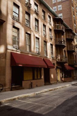 Dar ve rahat bir caddede balkonları olan alçak katlı taş bina, New York mimarisi.