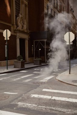 steam on urban street with vintage buildings and pedestrian crossing, atmosphere of new york city clipart