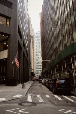 New York 'taki karanlık modern binaların yakınındaki dar cadde yoluna park edilmiş arabalar.
