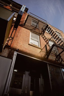 New York şehrinde yangın merdivenleri olan kırmızı tuğlalı binanın alçak açılı görüntüsü, klasik mimari.
