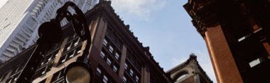 Sancak, New York 'ta gökyüzüne karşı modern ve klasik binaların yakınındaki fenerin düşük açılı görüntüsü