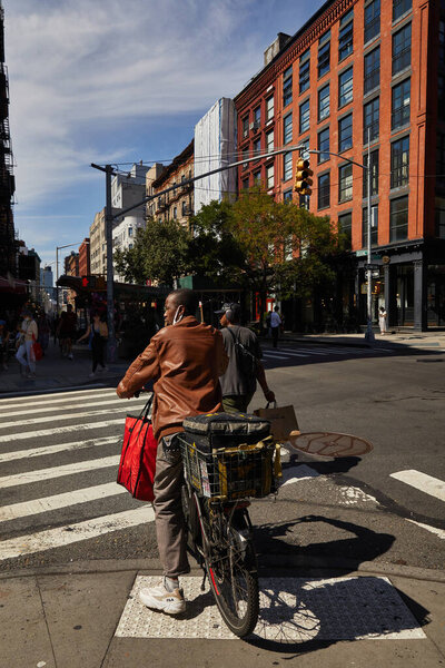 NEW YORK, USA - NOVEMBER 26, 2022: african american cyclist waiting on crossroad with traffic lights