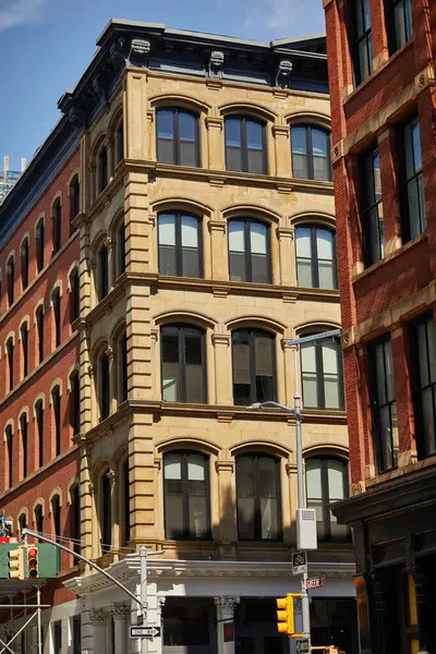 corner of vintage building with arch windows near traffic lights in downtown of new york city