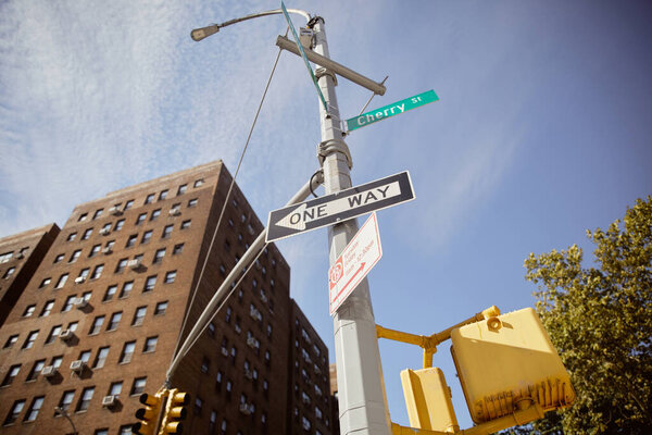 низкий угол обзора уличного полюса с дорожными знаками, показывающими направление возле здания из красного кирпича в Нью-Йорке