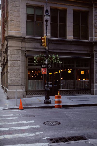 street pole with flowerpots and traffic lights near building with restaurant in new york city