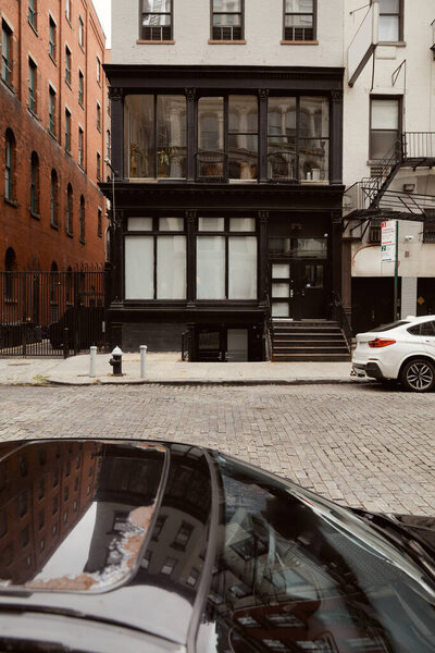 Modern cars parked on roadway near building with black and white exterior in new york city