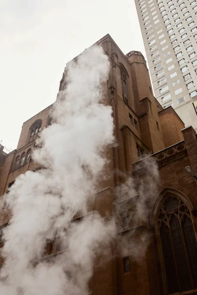 stock image steam near red brick catholic church and skyscraper on urban street of new york city, low angle view