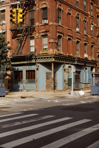 vintage building with fire escape stairs near pedestrian crossing in new york city, urban scene