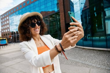 Şık bir kadın Avrupa 'da modern bir binanın önünde selfie çekiyor..