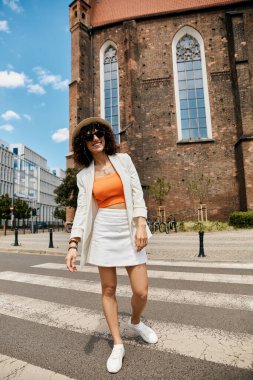 Beyaz ceketli ve etekli bir kadın Avrupa 'da yaya geçidinde yürüyor..