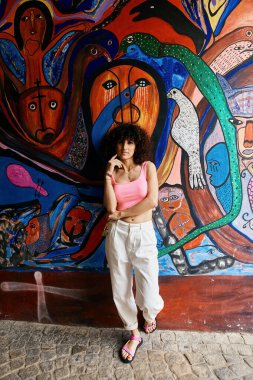 Şık giyinmiş bir kadın Avrupa 'da canlı, renkli bir duvar resmine karşı duruyor..