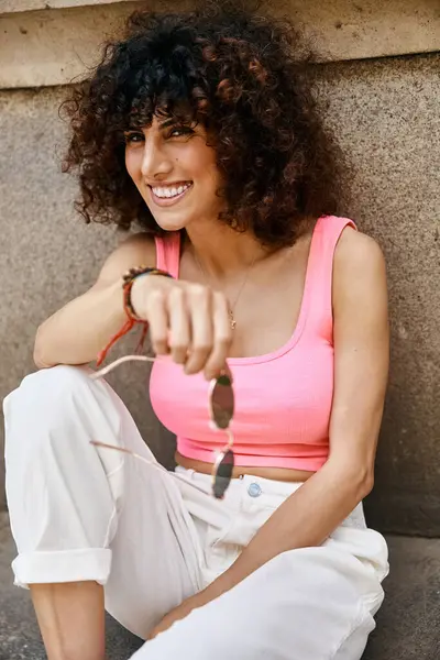 stock image A stylish woman enjoys a sunny day in Europe, radiating happiness in a pink top and white pants.