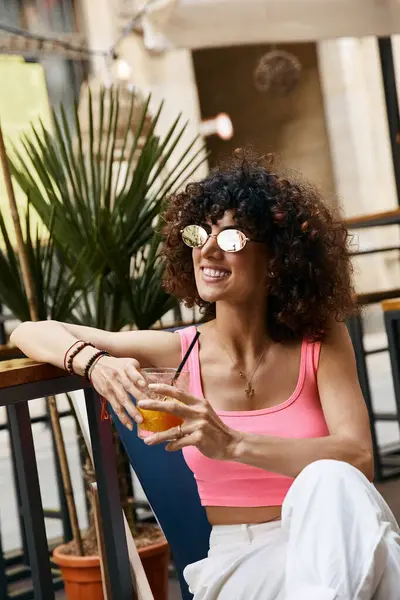 stock image A woman enjoys a drink while sitting outdoors in Europe.