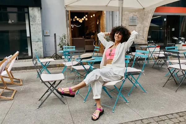 stock image A woman in stylish attire enjoys a sunny afternoon at a cafe in Europe.