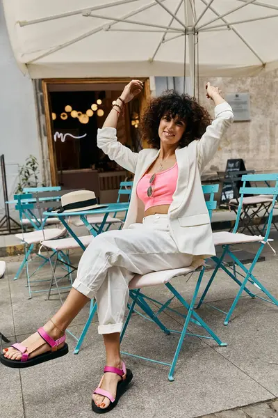 stock image A fashionable woman enjoys a break at a cafe in Europe, wearing a white blazer and sandals.