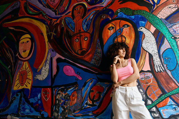 A stylish woman poses against a vibrant mural during her European travels.