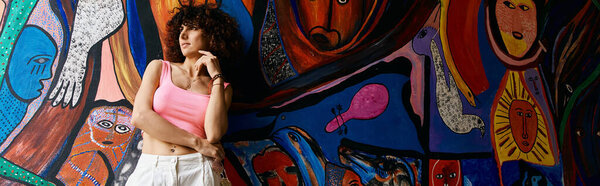 Женщина в стильной одежде восхищается красочной абстрактной фреской во время своих европейских путешествий.