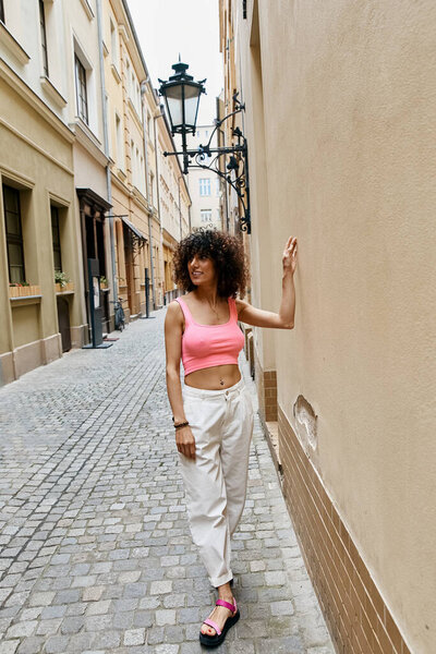 A woman in stylish attire explores a cobblestone alleyway in Europe.