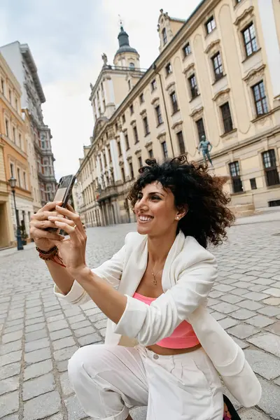 stock image A woman in stylish attire enjoys a European adventure, taking a phot.