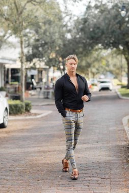 Yakışıklı sarışın bir adam şık giyinmiş. Orlando, Florida 'da bir sokakta yürüyor..