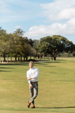 Şık giyinmiş sarışın bir adam Miami 'de golf sahasında yürüyor..