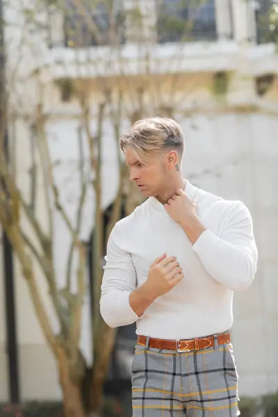 stock image A blonde man poses for a portrait on a sunny Florida street, wearing a white long-sleeved shirt and plaid pants.