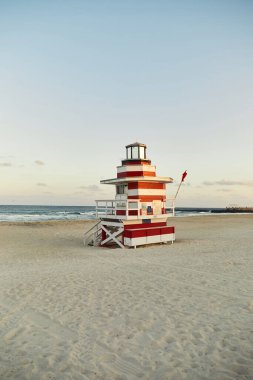 Miami, Florida 'da kumlu bir sahilde kırmızı ve beyaz bir cankurtaran ayakta duruyor..