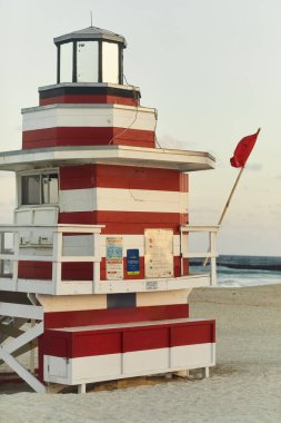 Yüzücüler için uyarı işareti veren, kırmızı bayrak sallayan klasik bir Miami sahili cankurtaranı..