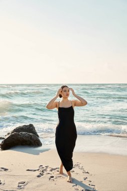 Miami Beach, Florida 'da siyah elbiseli genç bir kadın yürüyor..