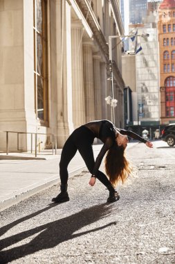 Siyahlı genç bir kadın New York 'ta bir caddede dans ediyor..