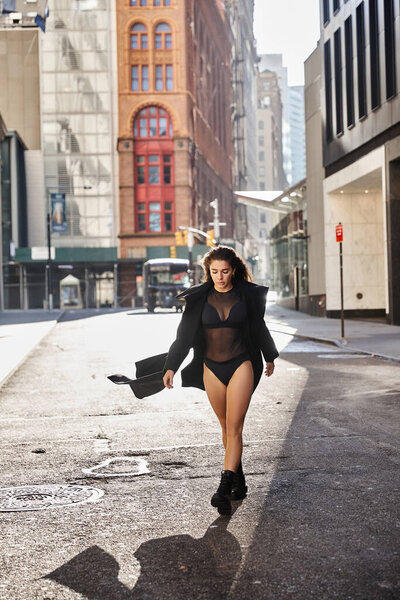 A young woman dances on a New York City street, her black coat billowing behind her.