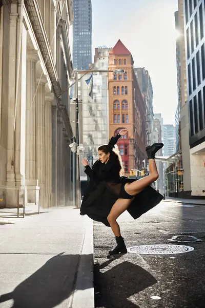stock image A young woman dances in the streets of New York City, her black outfit flowing in the wind.