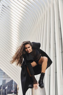 Siyah elbiseli genç bir kadın New York 'un göbeğindeki beton bir sütunun üzerinde dans ediyor..