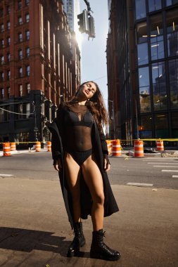 Siyah elbiseli ve çizmeli genç bir kadın New York sokaklarında dans ediyor..